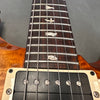 Close-up of electric guitar fretboard with bird inlays and black humbucker pickup on a sunburst wood body