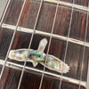Close-up of guitar fretboard with abalone mother-of-pearl bird inlay and steel guitar strings on dark wood fingerboard