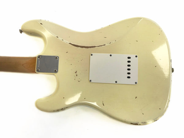 Back of cream vintage electric guitar body with visible wear and scratches, white plastic back plate, and metal neck plate on wooden neck
