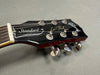 Close-up of Gibson Les Paul Standard electric guitar headstock with tuning pegs and strings on grey background