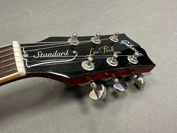 Close-up of Gibson Les Paul Standard electric guitar headstock with tuning pegs and strings on grey background