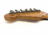 Close-up of vintage Fender Custom Shop guitar headstock with six tuning pegs and worn wood finish on a white background