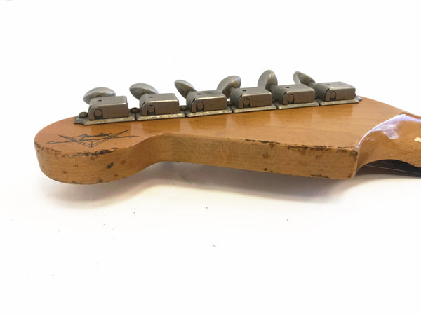 Close-up of vintage Fender Custom Shop guitar headstock with six tuning pegs and worn wood finish on a white background