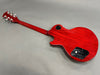 Back view of red electric guitar with solid wood body and chrome tuning pegs on gray background