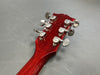 Close-up of red wooden guitar headstock with six silver tuning pegs on gray background, Coffee House Guitars product detail.