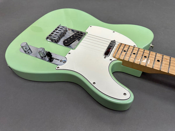 Seafoam green electric guitar with white pickguard and maple neck on gray background, close-up of body and controls