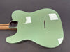 Back view of seafoam green electric guitar body with maple neck and string ferrules on gray background