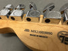 Close-up of Fender guitar headstock back showing serial number MX21003850, Made in Mexico stamp, and chrome tuning pegs with Fender logo.