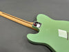 Rear view of seafoam green electric guitar with maple neck and chrome neck plate on gray background