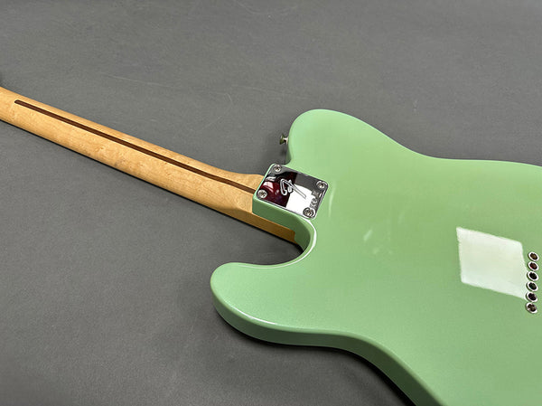 Rear view of seafoam green electric guitar with maple neck and chrome neck plate on gray background