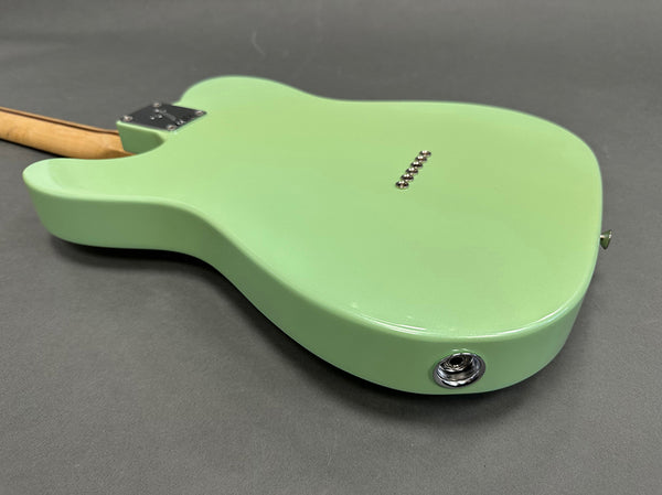 Light green electric guitar body back with maple neck and chrome hardware on gray background