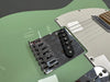 Close-up of green electric guitar body showing white pickguard, chrome bridge, and single-coil pickup at Coffee House Guitars product listing