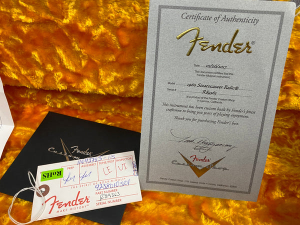 Fender Certificate of Authenticity for 1960 Stratocaster Relic guitar with serial number R89363, displayed on orange plush guitar case lining along with Fender Custom Shop tag and paperwork.