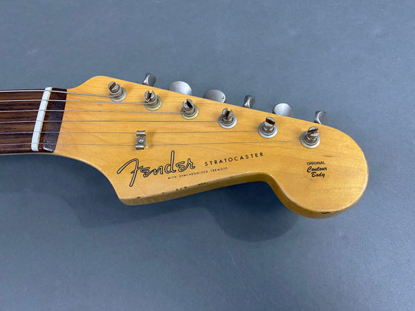 Fender Stratocaster guitar headstock with original contour body, vintage maple finish, and six tuning pegs on gray background