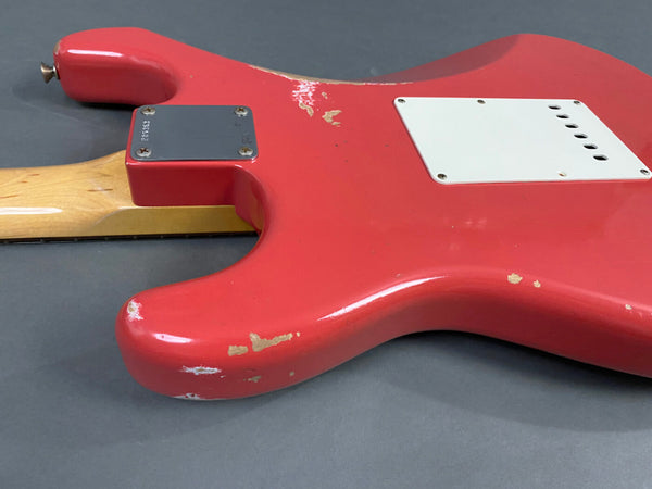 Close-up of red electric guitar body showing worn paint and white rear cover plate, vintage maple neck heel and metal neck plate screws on gray background