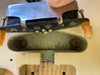 Close-up of vintage electric guitar single-coil pickup being removed from the pickup cavity showing aged pickup cover, screws, and worn guitar body wood.