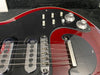 Close-up of red electric guitar body with two chrome pickups, bridge, multiple control knobs, and switches on black pickguard