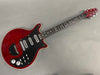 Red electric guitar with black pickguard and three single-coil pickups, chrome tuning pegs, and multiple control knobs on a gray background