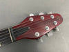 Close-up of RS Guitars red wooden electric guitar headstock with six tuning pegs and strings on gray background