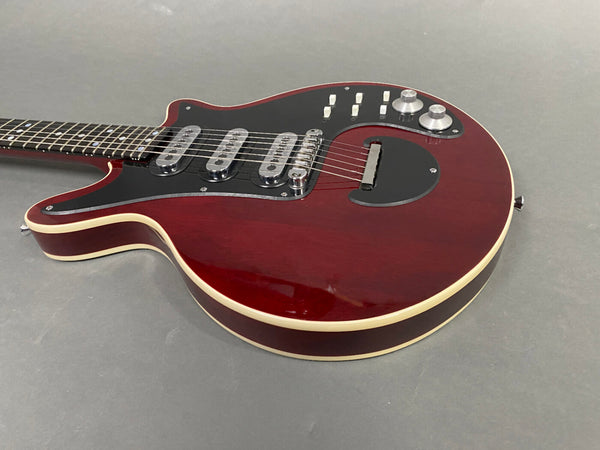 Electric guitar with deep red finish, triple single-coil pickups, black pickguard, and silver control knobs on gray background