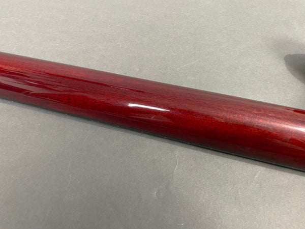 Glossy deep red guitar neck finish on gray surface close-up shot