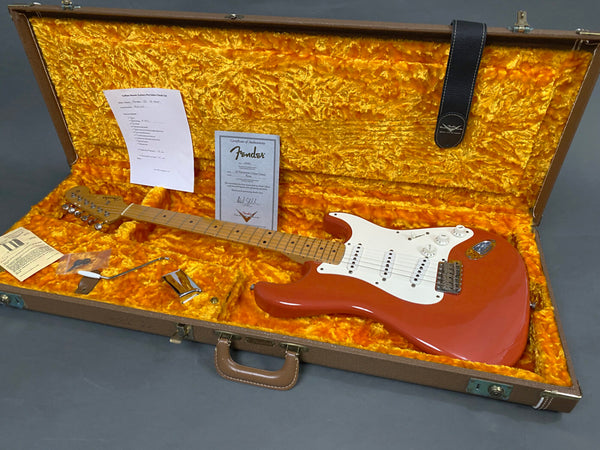 Fender electric guitar in red finish with maple neck and white pickguard inside vintage orange plush-lined hard case with certificate of authenticity and tremolo arm