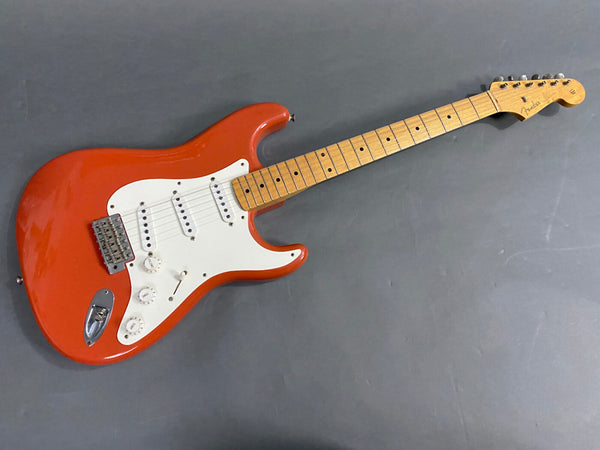 Fender Stratocaster electric guitar with red body, white pickguard, maple neck, and three single-coil pickups on gray background