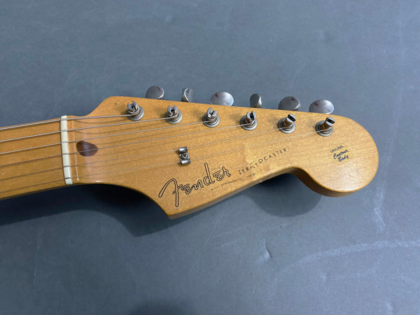 Close-up of a Fender Stratocaster guitar headstock with tuning pegs and strings, natural wood finish, original contour body logo visible