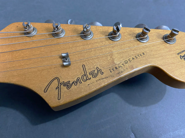 Close-up of vintage Fender Stratocaster guitar headstock with tuning pegs, showing Fender logo and strings on natural wood finish