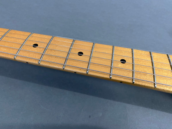 Close-up of maple guitar fretboard with metal frets and black dot inlays on blue background