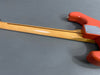 Back of electric guitar neck with smooth maple finish and orange guitar body on gray background