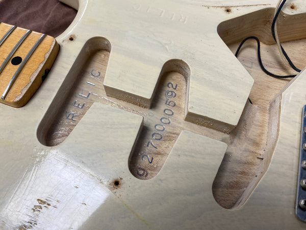 Close-up of vintage cream electric guitar body cavity showing serial number 9270000592 and partial maple neck with fret dots from Coffee House Guitars