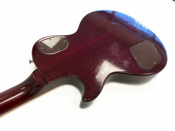 Back of vintage mahogany electric guitar body showing control cavity covers and wear scratches on dark red finish