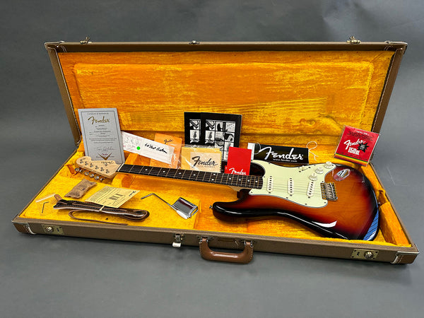 Fender Stratocaster electric guitar in sunburst finish inside vintage hardshell case with original Fender accessories, certificate of authenticity, and guitar strap on gold plush interior