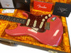 Fender Custom Shop pink Stratocaster electric guitar with tortoiseshell pickguard, white pickup covers, and control knobs, displayed in orange plush-lined hard case with Fender owner's manual and custom care booklet.