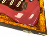 Close-up of worn red electric guitar body with white pickups and tortoiseshell pickguard in orange plush-lined guitar case