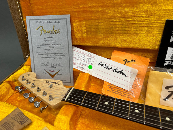 Certificate of Authenticity for Fender Custom 60's Stratocaster guitar inside orange plush guitar case with headstock and tuning pegs visible
