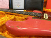Close-up of vintage pink Fender electric guitar body and fretboard in a plush yellow hard case with certification papers visible in the background