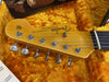 Close-up of Fender Stratocaster guitar headstock with tuning pegs and string tree in yellow plush-lined guitar case