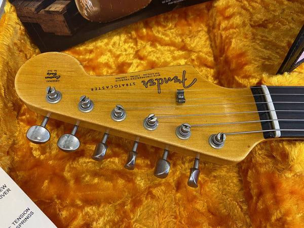 Close-up of Fender Stratocaster guitar headstock with tuning pegs and string tree in yellow plush-lined guitar case
