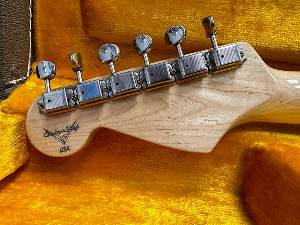 Maple guitar headstock with vintage-style tuning machines, Custom Shop USA logo, resting on plush yellow guitar case lining