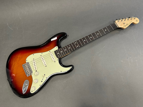 Fender Stratocaster electric guitar in sunburst finish with maple neck and rosewood fingerboard on gray surface