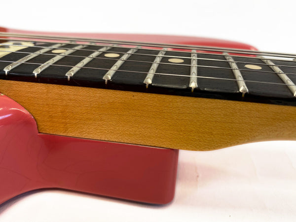 Close-up of guitar neck and fretboard showing detailed wood grain and metal frets on red electric guitar body