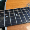 Close-up of acoustic guitar fretboard with mother-of-pearl dot inlays and steel strings on a natural wood body