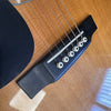 Close-up of acoustic guitar bridge with six white bridge pins and metal strings on natural wood body with black pickguard detail