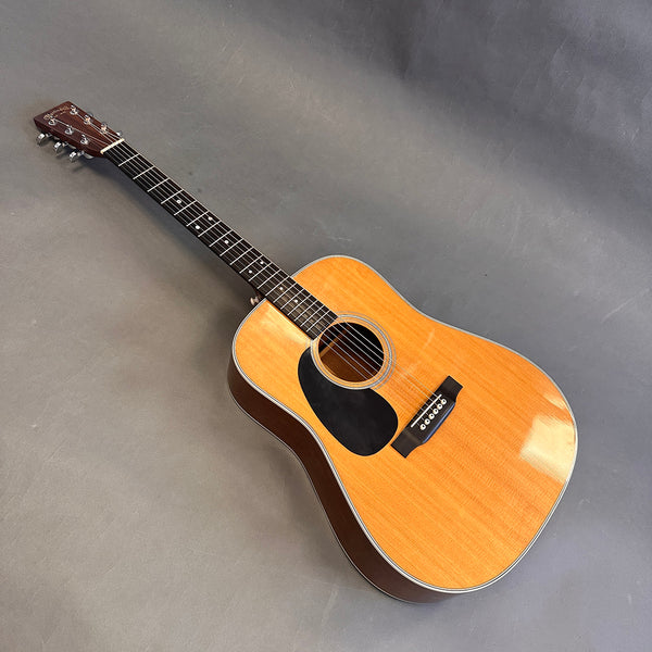 Martin D-28 natural finish dreadnought acoustic guitar with black pickguard and rosewood fretboard on gray background