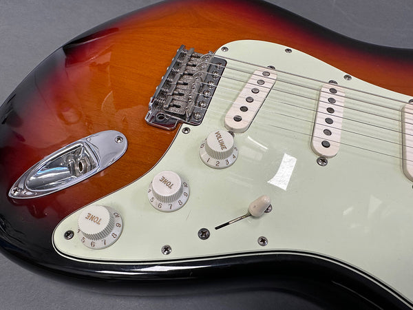 Close-up of sunburst electric guitar body showing white pickguard, three single-coil pickups, volume and tone control knobs, and metal bridge with strings at Coffee House Guitars.