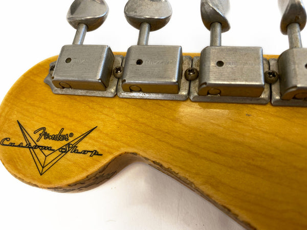 Close-up of vintage Fender Custom Shop guitar headstock showing Fender logo and tuning pegs with aged metal hardware on natural wood finish