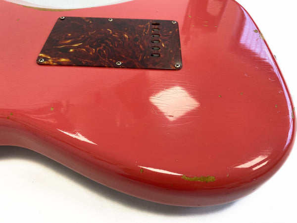 Close-up of worn red electric guitar body with tortoiseshell backplate showing scratches, paint chips, and finish cracks
