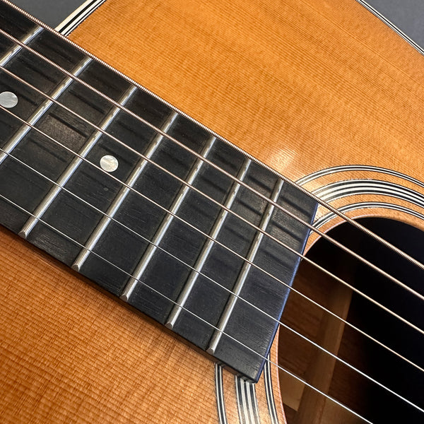 Close-up of acoustic guitar fretboard, strings, and sound hole with natural wood finish and decorative rosette at Coffee House Guitars